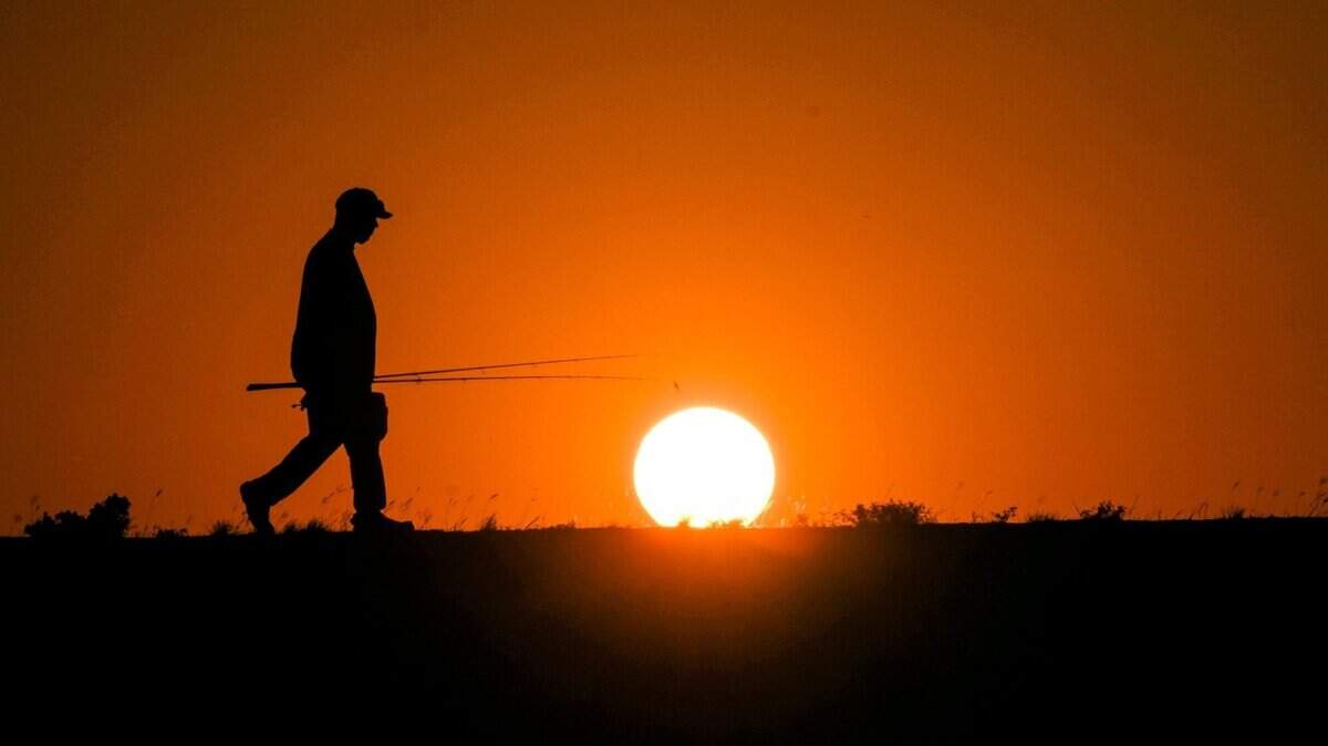 Nathaniel Robertson walks back to his car after fishing and braving the triple-digit warmth as the sun sets over Lake Pflugerville, Texas, on June 26, 2023. Nathaniel Robertson walks back to his car after fishing and braving the triple-digit warmth as the sun sets over Lake Pflugerville, Texas, on June 26, 2023.